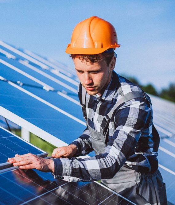 Workers installing solar panels on rooftop with wind turbine in background